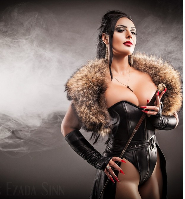 dominant woman in leather corset and fur collar holding a riding crop