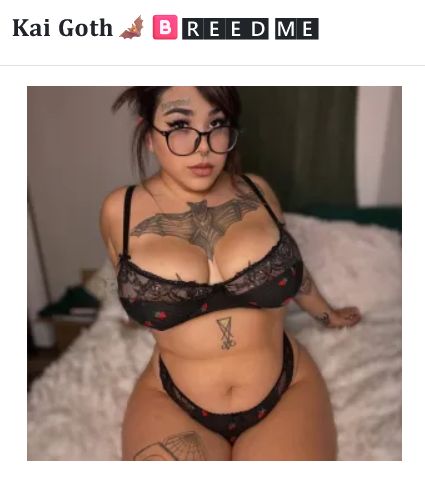 Kai Goth in black lace lingerie with tattoos sitting on bed