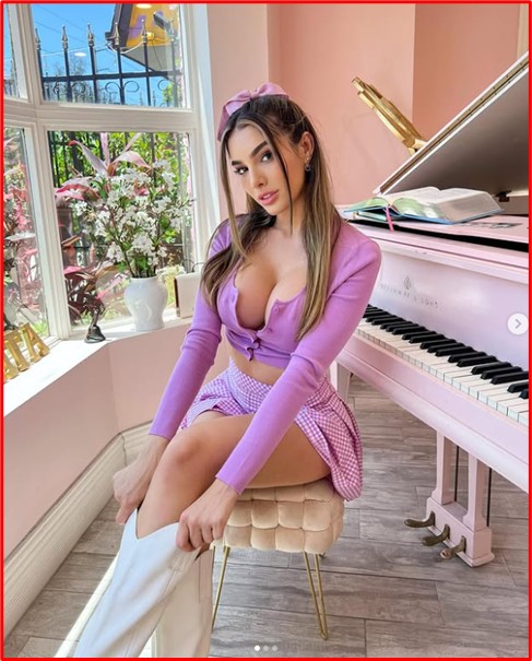 model in pastel outfit sitting by a pink piano, representing the Soft Girl aesthetic